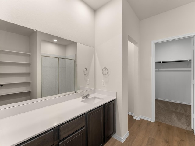 full bath featuring vanity, baseboards, a shower stall, wood finished floors, and a spacious closet