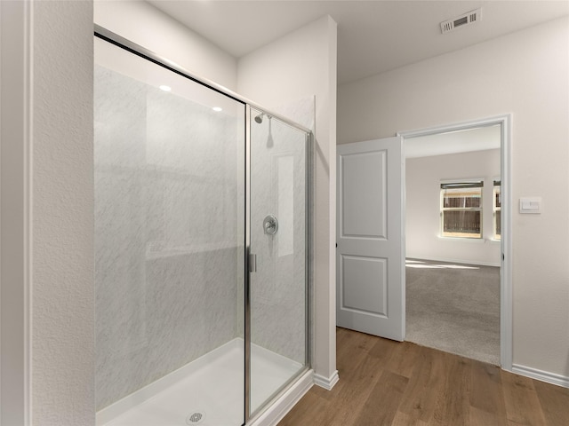 full bathroom with a shower stall, wood finished floors, and visible vents