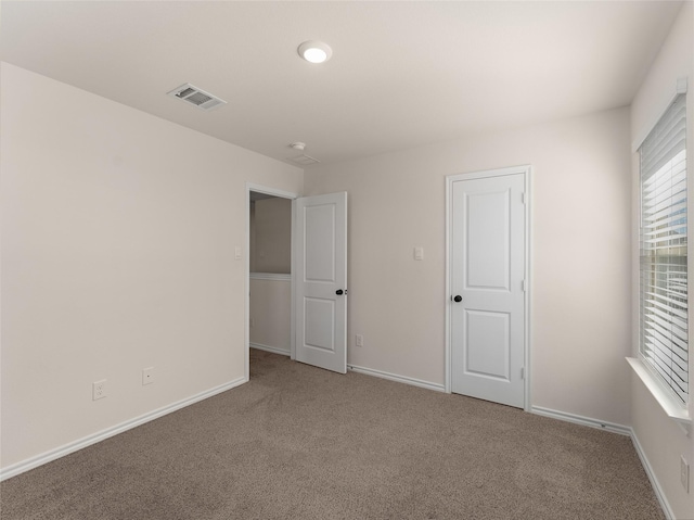 unfurnished bedroom featuring baseboards, multiple windows, carpet flooring, and visible vents