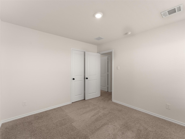 unfurnished bedroom with baseboards, visible vents, and light carpet