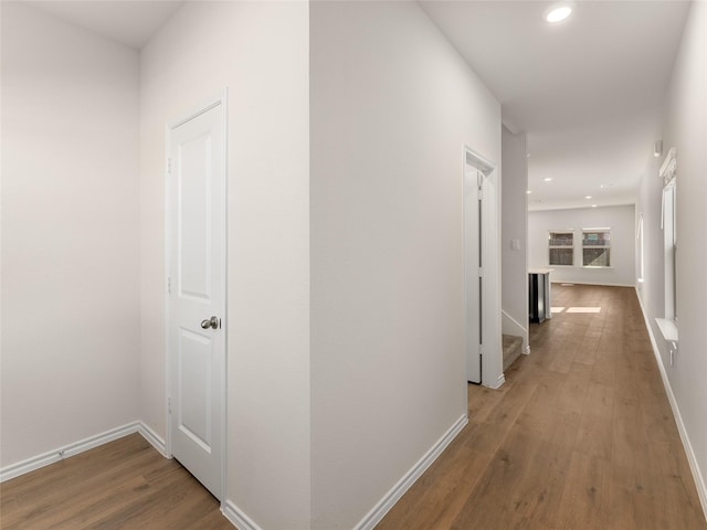 hallway featuring recessed lighting, baseboards, an upstairs landing, and wood finished floors