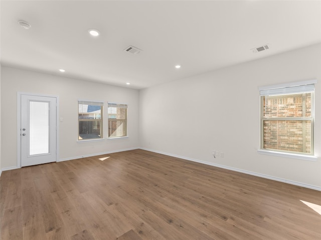unfurnished room with baseboards, visible vents, and wood finished floors