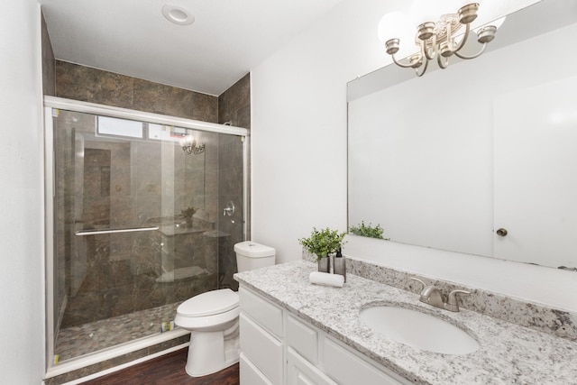 bathroom featuring a chandelier, hardwood / wood-style flooring, vanity, an enclosed shower, and toilet