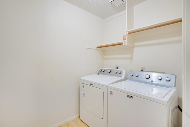 laundry room with washer and clothes dryer, light hardwood / wood-style floors, and a textured ceiling