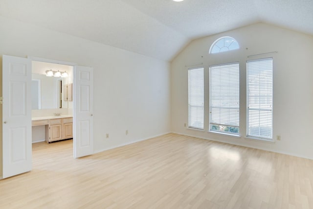 interior space featuring vaulted ceiling, light hardwood / wood-style flooring, and a textured ceiling