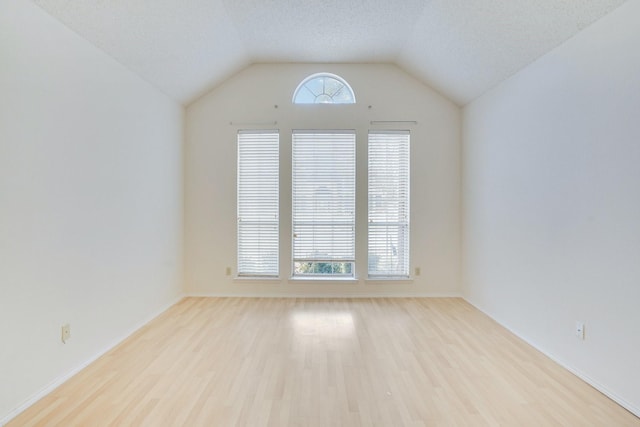 unfurnished room featuring vaulted ceiling, a textured ceiling, and light hardwood / wood-style flooring