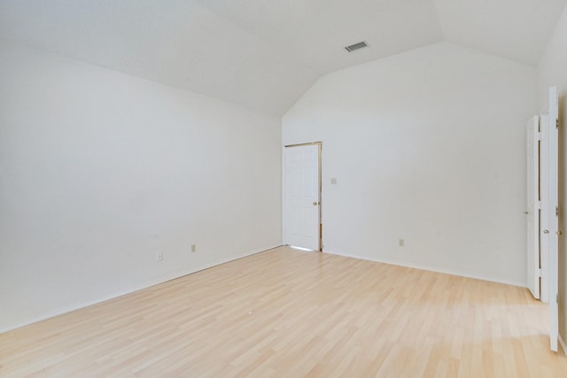 empty room with light hardwood / wood-style flooring and vaulted ceiling