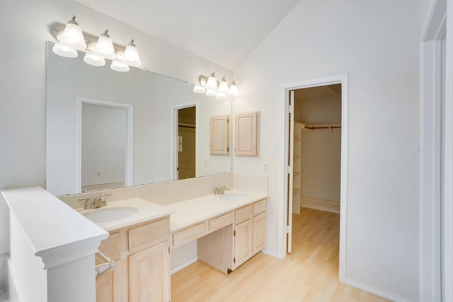 bathroom featuring lofted ceiling, wood-type flooring, vanity, and a textured ceiling