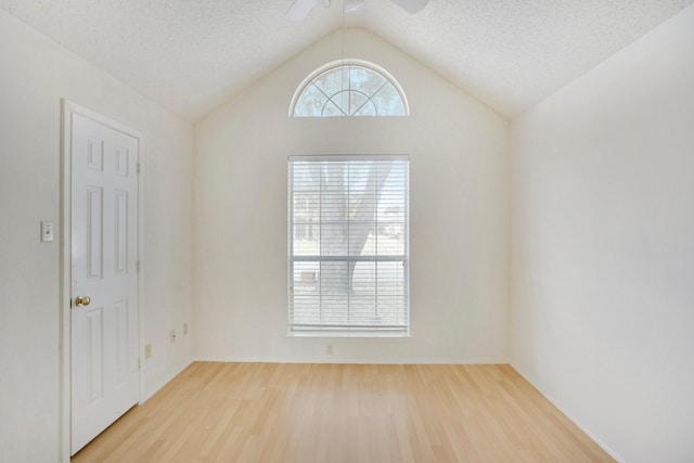 unfurnished room with vaulted ceiling, a healthy amount of sunlight, hardwood / wood-style floors, and a textured ceiling