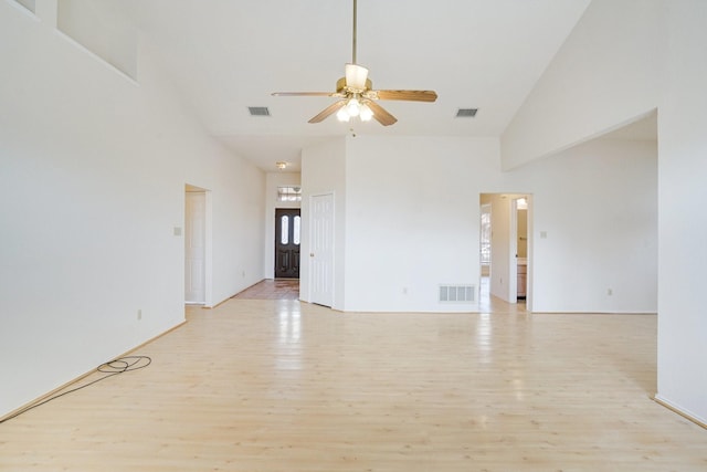 unfurnished room with ceiling fan, a towering ceiling, and light wood-type flooring