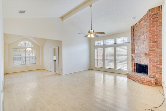 unfurnished living room with light hardwood / wood-style flooring, ceiling fan, lofted ceiling with beams, a textured ceiling, and a brick fireplace