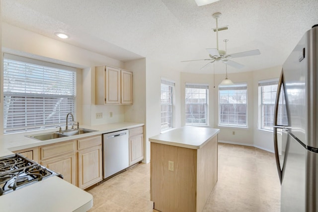 kitchen featuring light brown cabinetry, sink, a center island, stainless steel appliances, and a textured ceiling