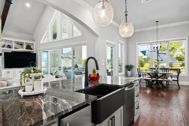 kitchen with dark stone countertops, sink, pendant lighting, and a wealth of natural light