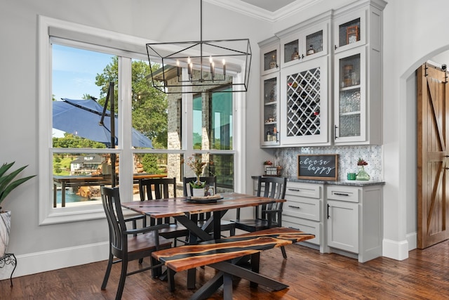 dining area with dark hardwood / wood-style flooring, a notable chandelier, ornamental molding, and a healthy amount of sunlight