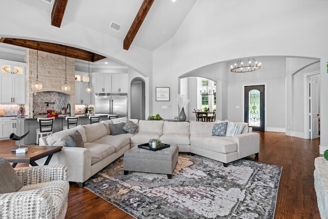 living room with an inviting chandelier, beam ceiling, dark hardwood / wood-style flooring, and a high ceiling