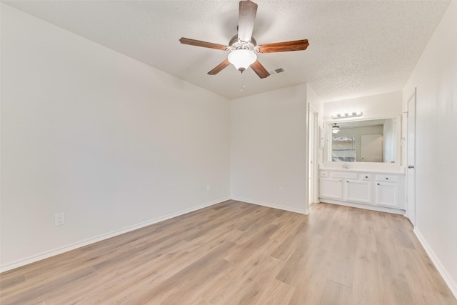 spare room with ceiling fan, light hardwood / wood-style floors, and a textured ceiling