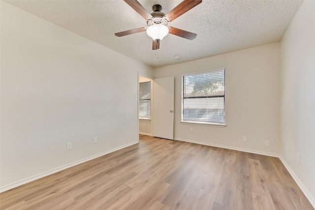 unfurnished room with ceiling fan, a textured ceiling, and light wood-type flooring