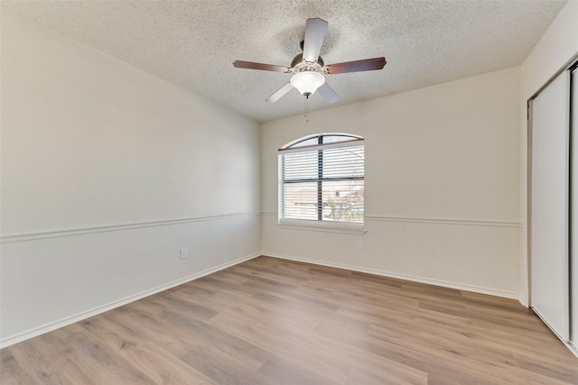 unfurnished bedroom featuring ceiling fan, a closet, a textured ceiling, and light wood-type flooring