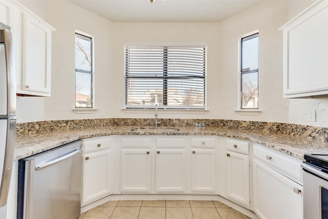 kitchen with light stone counters, appliances with stainless steel finishes, sink, and white cabinets