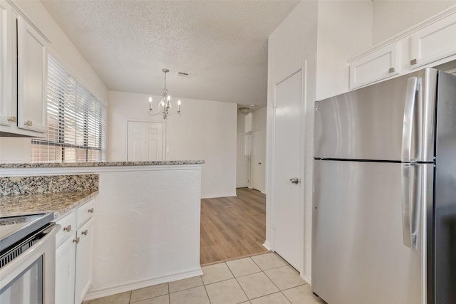 kitchen with white cabinetry, light tile patterned floors, stainless steel appliances, light stone countertops, and a textured ceiling