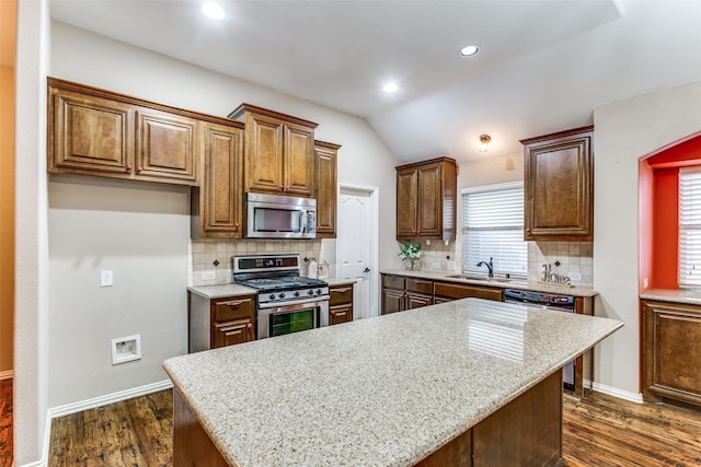 kitchen with light stone countertops, a kitchen island, stainless steel appliances, and dark wood finished floors