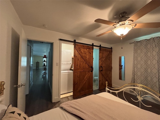 207 Granbury Ct, Granbury, TX 76049 - bedroom featuring stacked washer / drying machine, a barn door, dark wood finished floors, ensuite bathroom, and ceiling fan