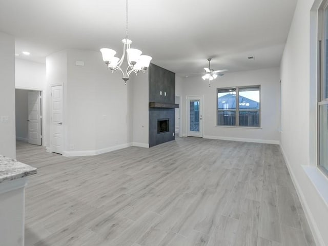 unfurnished living room with ceiling fan with notable chandelier, a fireplace, and light hardwood / wood-style floors