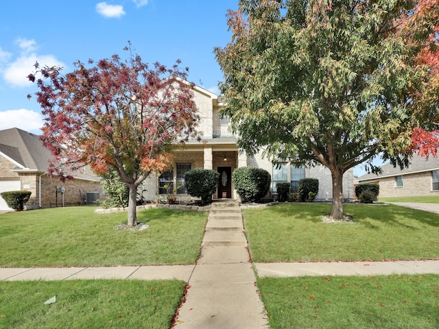 view of property hidden behind natural elements featuring a front yard and central air condition unit