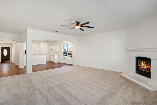 unfurnished living room featuring dark colored carpet and ceiling fan