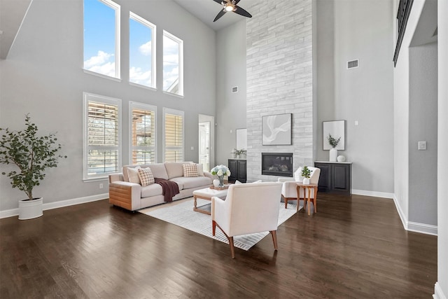 living area with a fireplace, baseboards, a ceiling fan, and wood finished floors