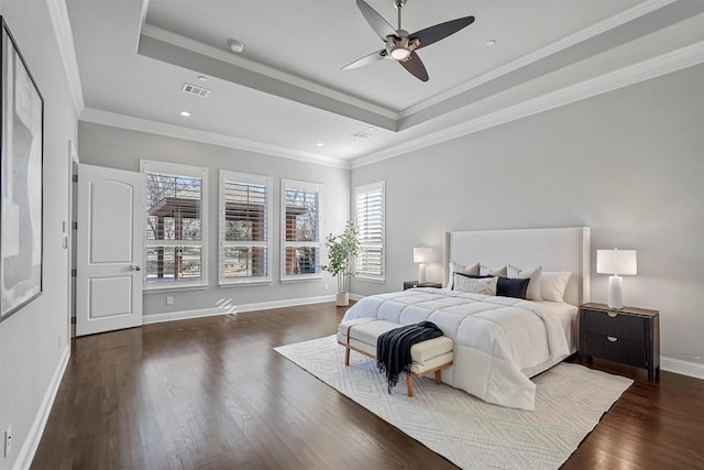 bedroom with wood finished floors, visible vents, baseboards, a tray ceiling, and crown molding