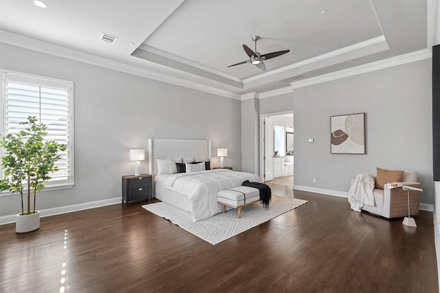 bedroom with wood finished floors, visible vents, baseboards, ornamental molding, and a raised ceiling