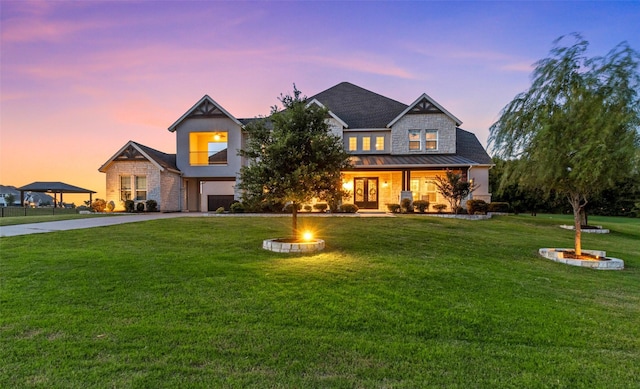 view of front of house with a standing seam roof, concrete driveway, an attached garage, and a front lawn