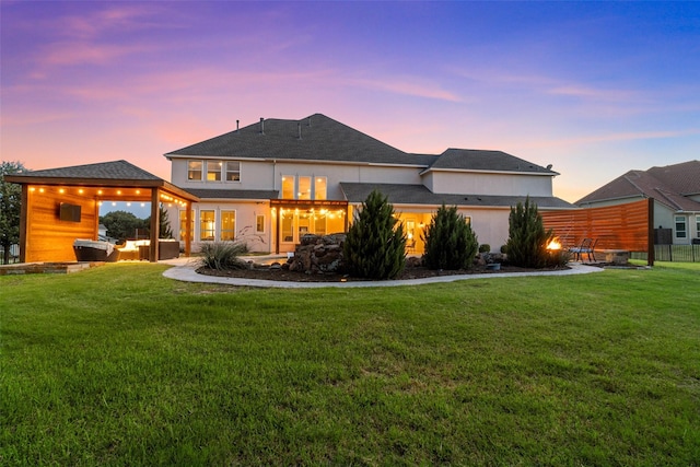 back of house at dusk featuring a yard, a patio, and stucco siding