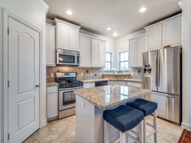 kitchen featuring white cabinetry, stainless steel appliances, a center island, and decorative backsplash