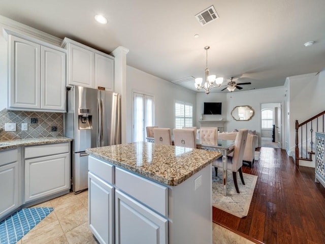 kitchen with pendant lighting, white cabinets, backsplash, a center island, and stainless steel fridge with ice dispenser