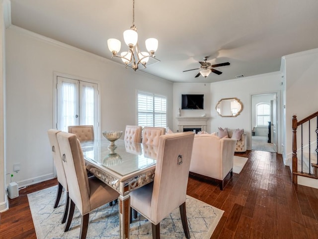 dining area featuring crown molding, ceiling fan with notable chandelier, and dark hardwood / wood-style flooring