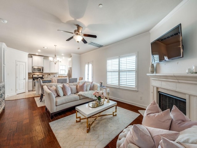 living room featuring ornamental molding, dark wood-type flooring, ceiling fan with notable chandelier, and a high end fireplace