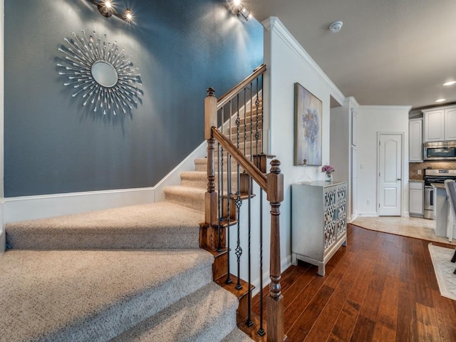 stairway with ornamental molding and hardwood / wood-style floors