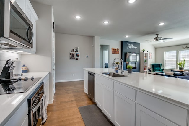 kitchen featuring sink, light hardwood / wood-style flooring, appliances with stainless steel finishes, tasteful backsplash, and white cabinets