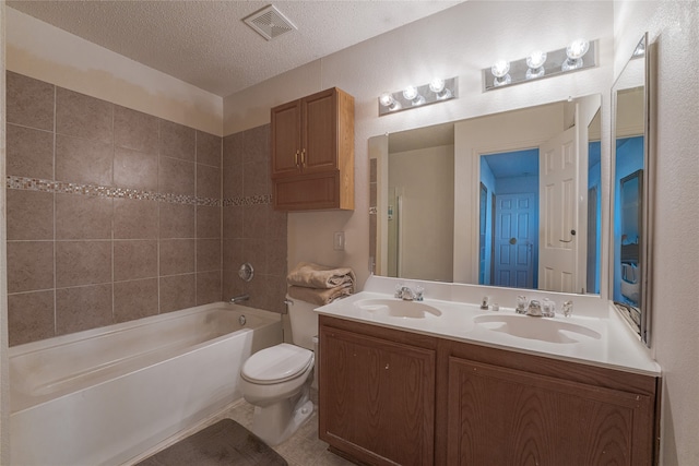 full bathroom featuring toilet, a textured ceiling, vanity, tiled shower / bath combo, and tile patterned flooring