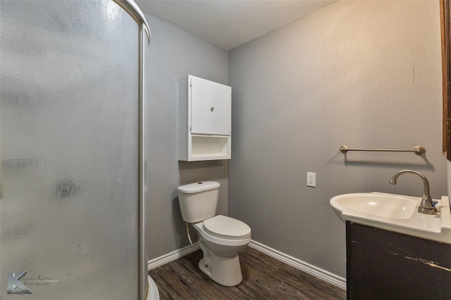 bathroom with hardwood / wood-style flooring, vanity, a textured ceiling, a shower with shower door, and toilet