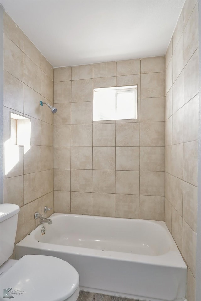 bathroom featuring tiled shower / bath combo and toilet