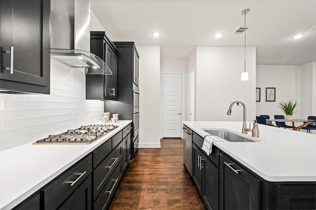 kitchen featuring decorative light fixtures, sink, dark hardwood / wood-style flooring, stainless steel appliances, and wall chimney range hood