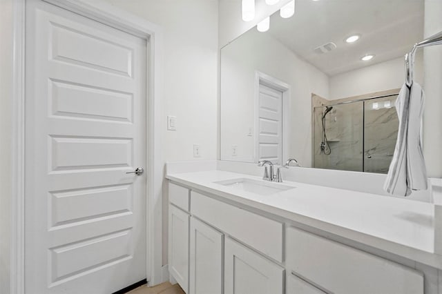 bathroom featuring a shower with door and vanity