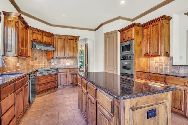 kitchen with light tile patterned flooring, sink, appliances with stainless steel finishes, a kitchen island, and wall chimney range hood