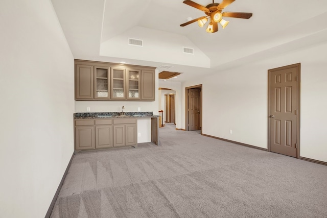 kitchen with lofted ceiling, sink, light colored carpet, dark stone countertops, and ceiling fan