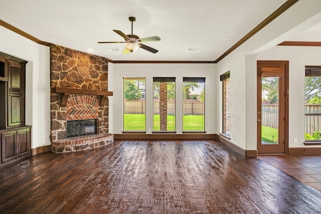 unfurnished living room featuring dark hardwood / wood-style floors, ceiling fan, a stone fireplace, and crown molding