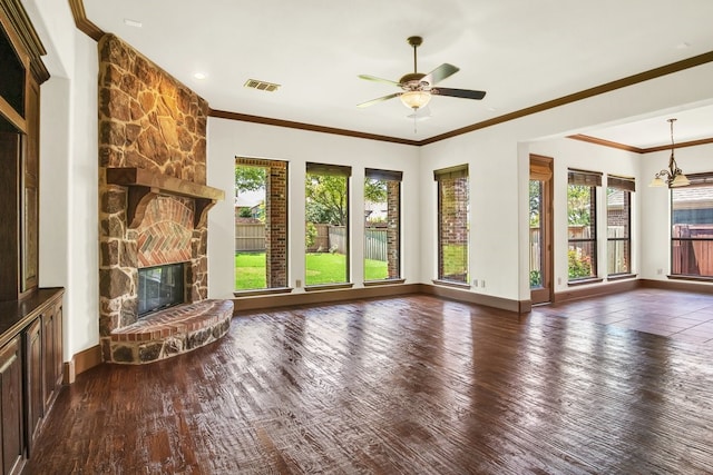 unfurnished living room with ornamental molding, a stone fireplace, ceiling fan with notable chandelier, and dark hardwood / wood-style flooring