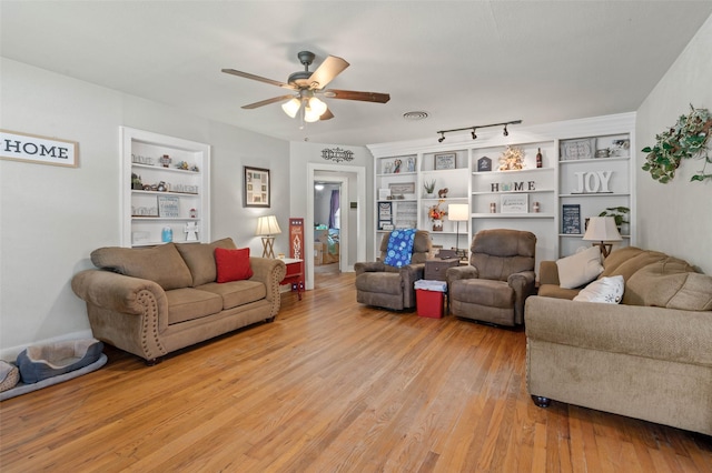 living room with built in shelves, light hardwood / wood-style flooring, and ceiling fan